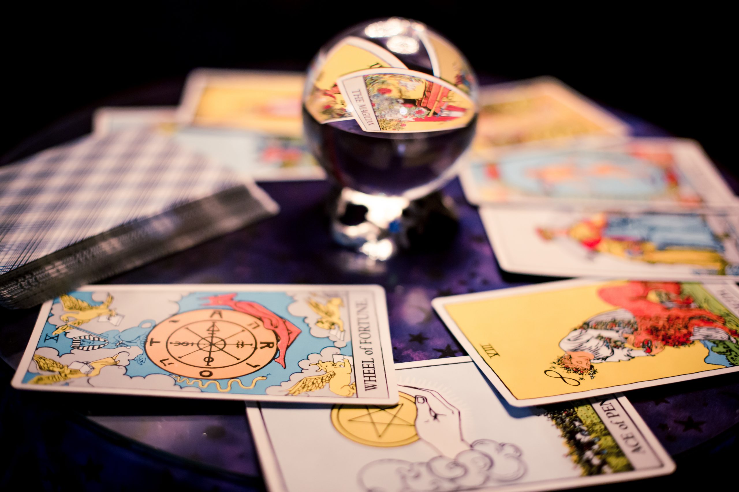 Antique tarot cards spread on a purple table surrounding crystal ball for Halloween